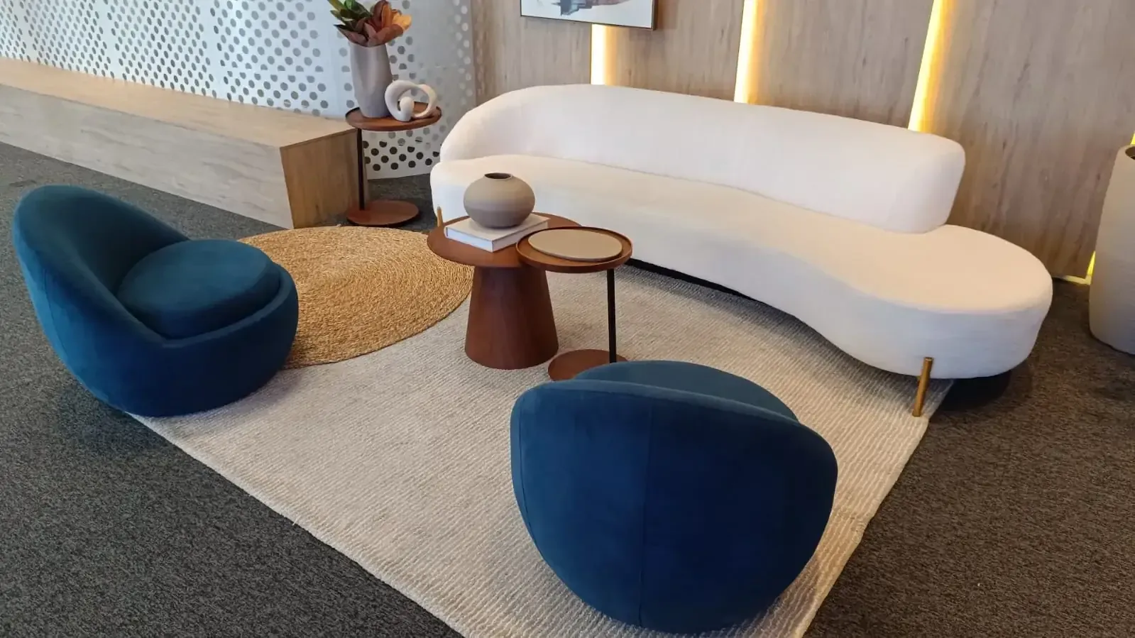 Sofá curvo branco e poltronas de veludo azul em sala de estar