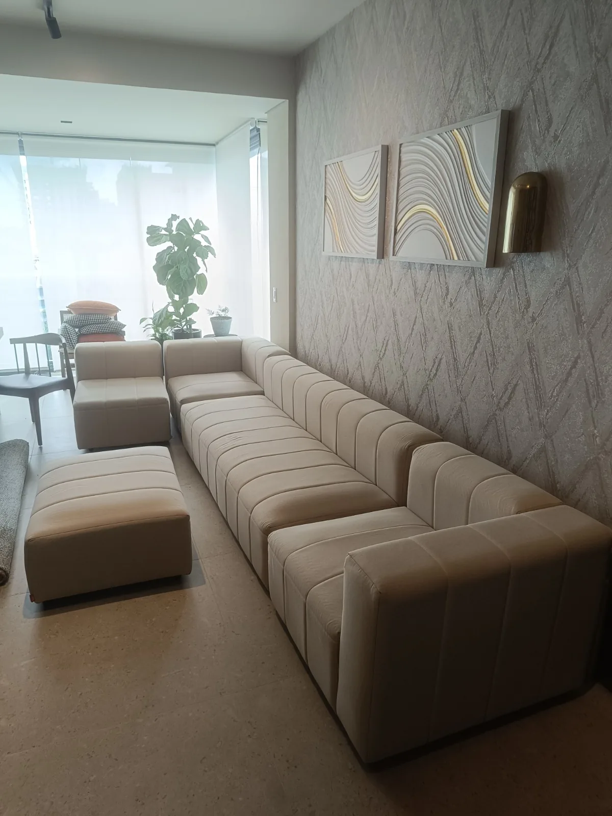 Sofá modular bege com almofadas em sala ampla